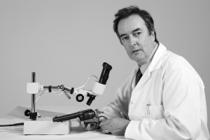 Forensic Scientist examines gun for evidence in a laboratory environment.