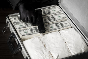Criminal with gun and briefcase full of money and drugs