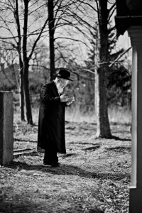 Lonely religious Jew prays at the grave in the old cemetery in Lezajsk